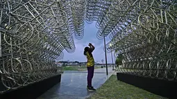 Seorang pria mengambil gambar instalasi seni seniman China Ai Weiwei yang berjudul 'Forever Cycles' di Rio de Janeiro, Brasil, Senin (19/8/2019). Instalasi Ai Weiwei ini akan dibuka pada 21 Agustus 2019. (CARL DE SOUZA/AFP)