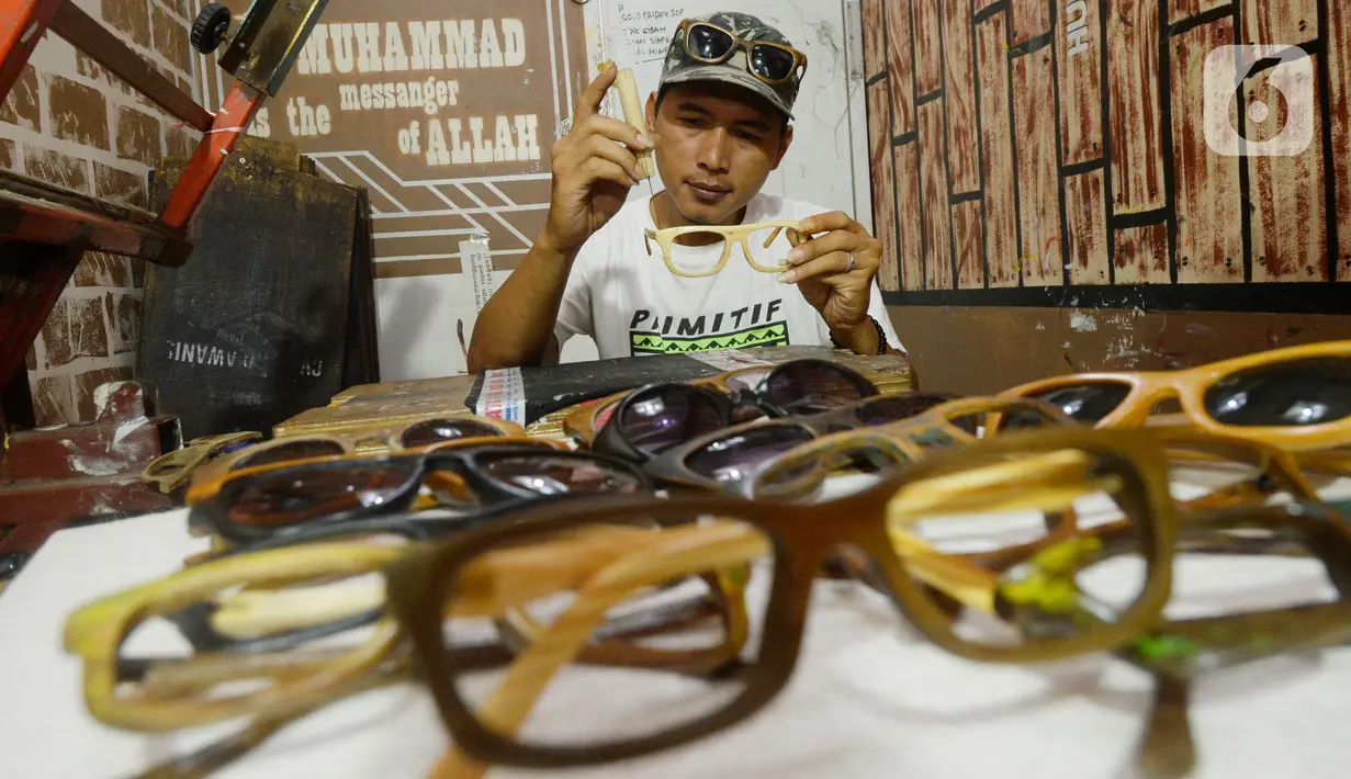 Perajin Yuyud Wahyudi (39) menyelesaikan pembuatan frame kacamata dari limbah kayu bekas di Pondok Benda, Pamulang, Tangsel, Kamis (8/10/2019). Sebelum pandemi, Yuyud menerima banyak pesanan seperti dari Italia, Norwegia, Prancis dan Jerman, namun kini turun hingga 75 persen. (merdeka.com/Dwi Narwok