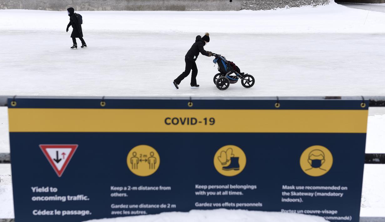 Para pemain skateboard melewati tanda tentang tindakan COVID-19 di Rideau Canal Skateway pada hari pembukaannya di Ottawa, Ontario, Kamis (28/1/2021). Kanal Rideau adalah Situs Warisan Dunia UNESCO. (Justin Tang/The Canadian Press via AP)