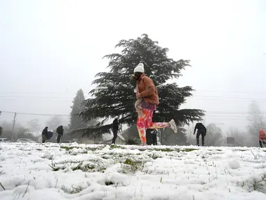 Orang-orang menikmati hujan salju pertama musim ini di Katoomba di pegunungan Blue Mountains, Kamis (10/6/2021). Katoomba berada di New South Wales, selatan Australia atau 102 kilometer sebelah barat Sydney.  (AFP/Saeed KHAN)