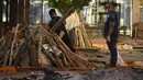 Staf meletakkan kayu bakar di atas tumpukan kayu korban Covid-19 di Krematorium Nigambodh Ghat, New Delhi, Kamis (22/4/2021). India sekarang menjadi negara terparah kedua di dunia setelah AS, dengan kasus baru lebih dari 200.000 infeksi baru setiap hari selama sepekan terakhir. (Sajjad HUSSAIN/AFP)