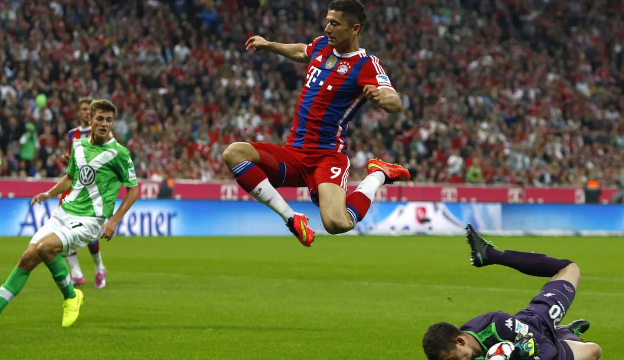 Pemain depan Bayern Munich, Robert Lewandowski, melompati penjaga gawang VfL Wolfsburg, Max Gruen, saat berlaga dilanjutan Bundesliga di Allianz Arena, (23/8/2014). (REUTERS/Michaela Rehle)