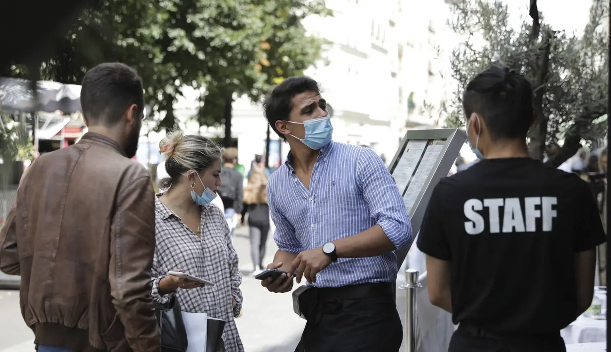 Pengunjung menunjukkan kartu kesehatan mereka di sebuah restoran di Paris, Senin (9/8/2021). Prancis mewajibkan semua orang menunjukkan kode QR yang membuktikan mereka memiliki Kartu Vaksinasi untuk memasuki restoran dan kafe atau bepergian di negara tersebut. (AP Photo/Adrienne Surprenant)