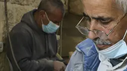 Para tukang kayu Palestina mengukir patung keagamaan dari kayu zaitun di sebuah toko dekat Church of the Nativity, Betlehem, Tepi Barat, 21 Desember 2020. Bahan dasar pembuatan patung tersebut menggunakan kayu zaitun. (HAZEM BADER/AFP)