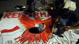 Aktivis membuat mural saat saat peringatan 20 tahun reformasi di Silang Monas Barat Laut, Jakarta, Senin (21/5). Dalam aksinya, mereka mendesak pemerintah segera menuntaskan seluruh agenda reformasi. (Liputan6.com/Helmi Fithriansyah)