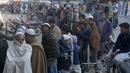 Orang-orang berdiri dalam antrean panjang dan menunggu untuk membeli sekarung tepung terigu bersubsidi dari titik penjualan di Peshawar, Pakistan, Senin, 9 Januari 2023. Orang-orang menderita akibat kenaikan harga tepung terigu di Pakistan baru-baru ini. (AP Photo/Muhammad Sajjad)