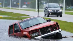 Sebuah kendaraan terendam di selokan di sebelah jalan raya yang hampir banjir saat jalur luar Badai Ida tiba di Bay Saint Louis, Miss (29/8/2021). Pusat Badai Nasional (NHC) AS mengatakan topan Ida mendarat di dekat Port Fourchon, Louisiana, pada pukul 11:55 waktu setempat. (AP Photo/Steve Helber)