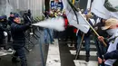 Polisi menyemprotkan merica saat aksi menolak Reformasi Pensiun di Brussels, Belgia, Selasa (15/11). Mereka menolak rencana pemerintah yang akan menaikkan usia pensiun dari 56 menjadi 63 tahun. (REUTERS / Yves Herman)