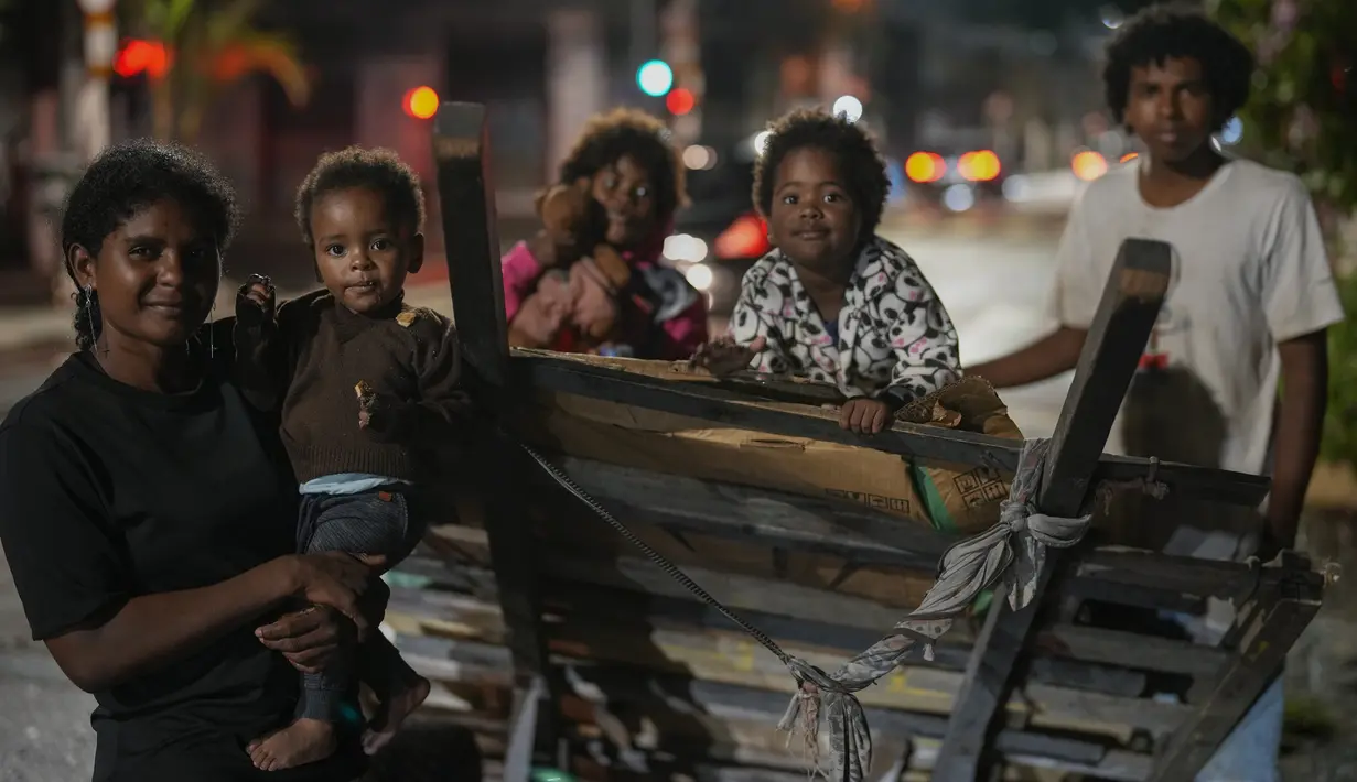 Sheila Carvalho de Souza yang bekerja mengumpulkan barang-barang di jalan, berpose bersama anak-anaknya dekat komunitas penghuni liar tempat mereka tinggal di Sao Paulo, 26 Januari 2022. Sensus baru menunjukkan populasi tunawisma di Sao Paulo meningkat 30% selama pandemi. (AP Photo/Andre Penner)