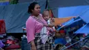 Seorang wanita membawa anaknya di tempat penampungan pengungsi korban gempa bumi di Lombok Utara,  NTB, Rabu (8/8). Lebih dari 70.000 orang kehilangan tempat tinggal akibat gempa Lombok berkekuatan 7 SR yang melanda pada Minggu (5/8). (AP/Tatan Syuflana)