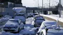 Kendaraan yang terdampar tertutup salju selama tiga hari di sepanjang jalan tol Attiki Odos, yang menghubungkan Athena dengan bandara, Yunani, Rabu (26/1/2022). Pihak berwenang berupaya membersihkan jalan yang terblokir dan memulihkan aliran listrik yang padam. (AP/Thanassis Stavrakis)