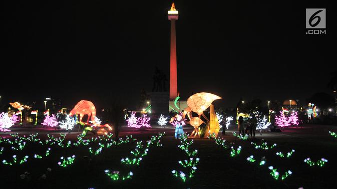 Pengunjung mengabadikan momen di depan salah satu lampion yang ditampilkan dalam Festival of Light di Monumen Nasional (Monas), Jakarta, Rabu (14/8/2019). (merdeka.com/Iqbal S. Nugroho)