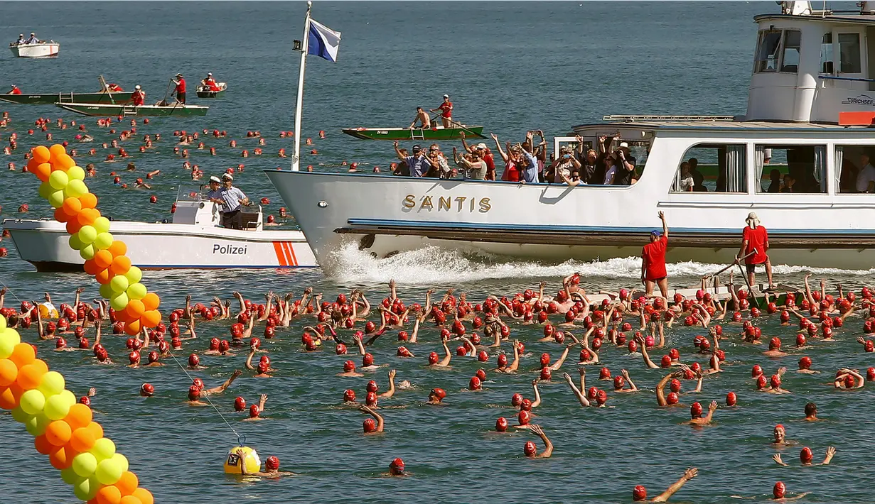 Para wisatawan melihat lomba berenang di Zurich, Swiss (24/8). Peserta mulai dari anak muda hingga orang tua bersaing menyebrangi Danau Zurich, Swiss. (REUTERS/Arnd Wiegmann)