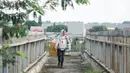 Seorang pria tanpa mengenakan masker melintasi Jembatan Penyeberangan Orang di Kawasan Jakarta, Selasa (19/5/2020). Sanksi PSBB yang kurang tegas menyebabkan sebagian warga masih bebas beraktivitas tanpa masker, meskipun resiko penyebaran virus corona masih tinggi. (Liputan6.com/Immanuel Antonius)