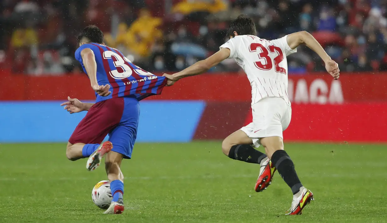 Gelandang Sevilla, Juan Luis Sánchez Velasco menarik kaus pemain Barcelona, Abde Ezzalzouli pada pertandingan La Liga Spanyol di stadion Ramon Sanchez-Pizjuan, Spanyol, Rabu (22/12/2021). Hasil ini tidak mengubah posisi Barcelona pada peringkat ketujuh dengan 28 poin. (AP Photo/Angel Fernandez)