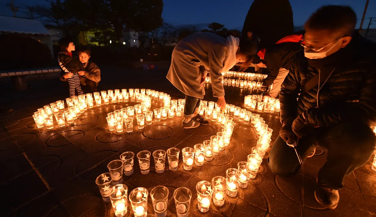 Seorang pria menyalakan lilin yang membentuk angka 3.11 saat upacara peringatan bencana gempa tsunami yang terjadi pada tahun 2011 di Natori, Prefektur Miyagi, Jepang (11/3). Dalam peristiwa tersebut sekitar 18 ribu orang tewas. (AFP/Kazuhiro Nogi)