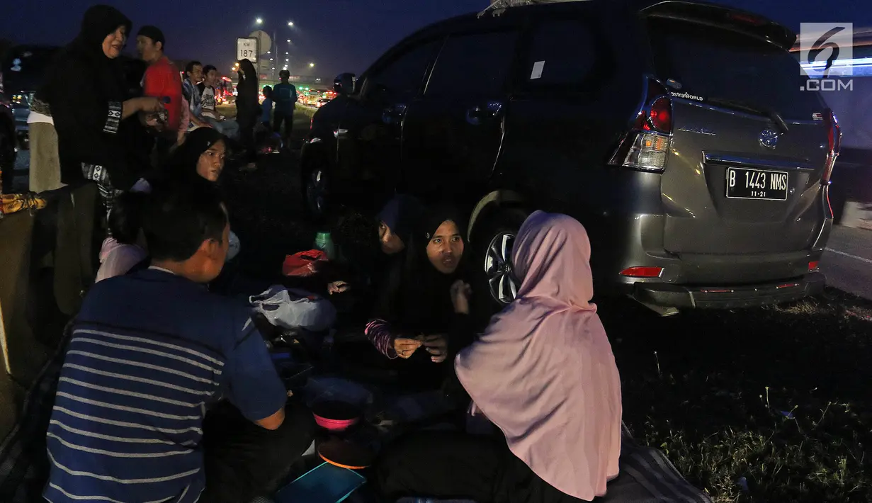 Pemudik menikmati makanan untuk berbuka puasa sembari beristirahat di pinggir ruas jalan tol Cipali KM 187, Kabupaten Cirebon, Jawa Barat, Kamis (30/5/2019). Sejumlah pemudik memilih menggunakan bahu jalan ruas tol untuk berbuka puasa karena penuhnya rest area. (Liputan6.com/Herman Zakharia)