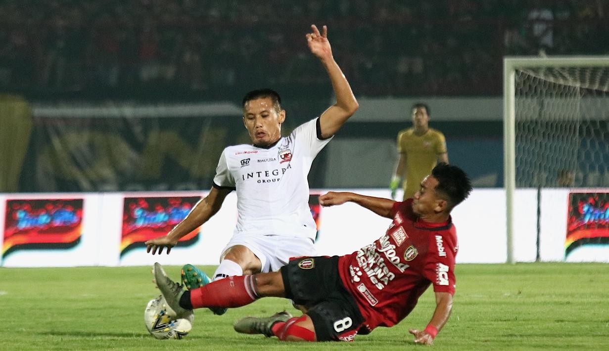 Gelandang Bali United, Muhammad Taufiq, berebut bola dengan gelandang Madura United, Guntur Ariyadi, pada laga Liga 1 2019 di Stadion Kapten I Wayan Dipta, Bali, Minggu (22/12). Bali kalah 0-2 dari Madura. (Bola.com/Aditya Wany)