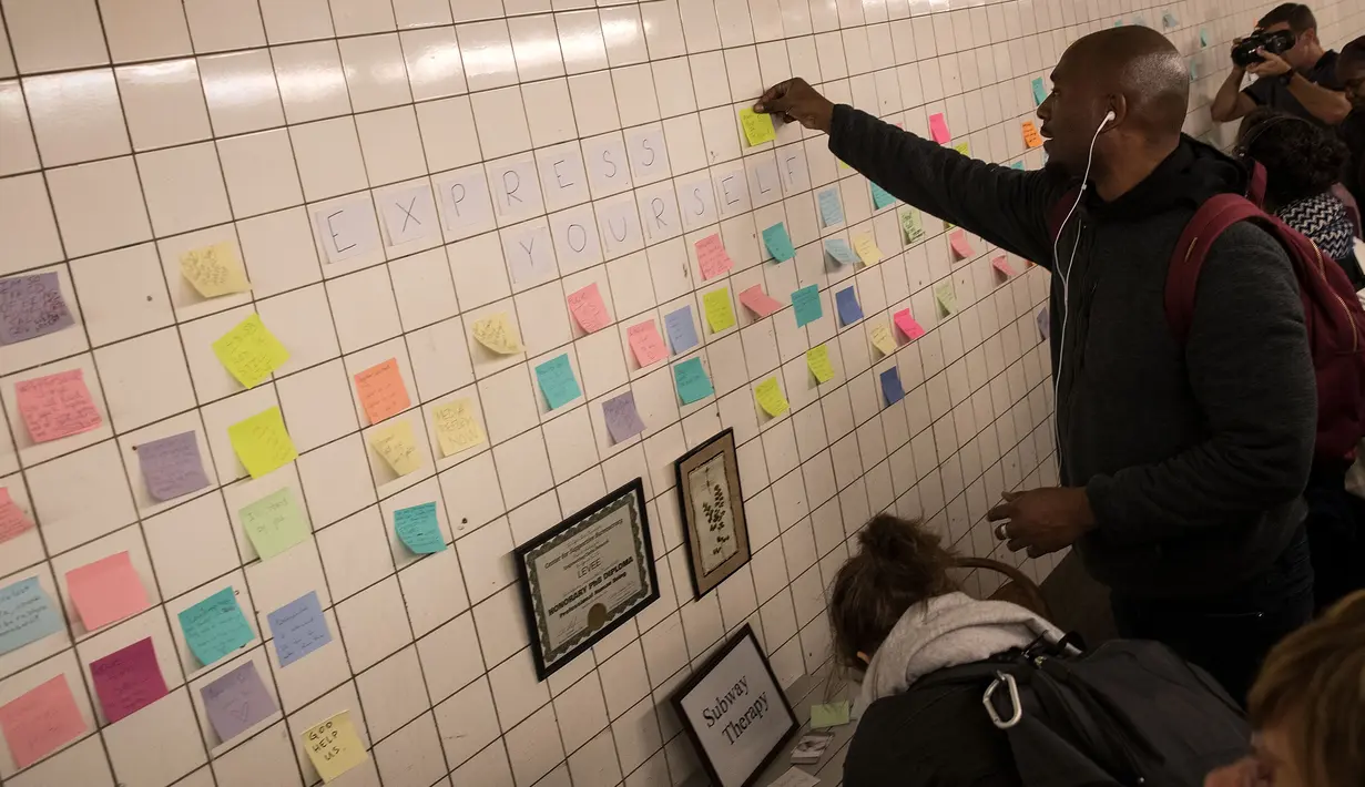 Sejumlah warga menempelkan post-it sebagai bagian 'subway therapy' di dinding stasiun Union Square, New York, Kamis (10/11). Subway therapy digunakan kaum komuter yang kesal dan kecewa dengan terpilihnya Donald Trump sebagai Presiden AS (DREW ANGERER/AFP)