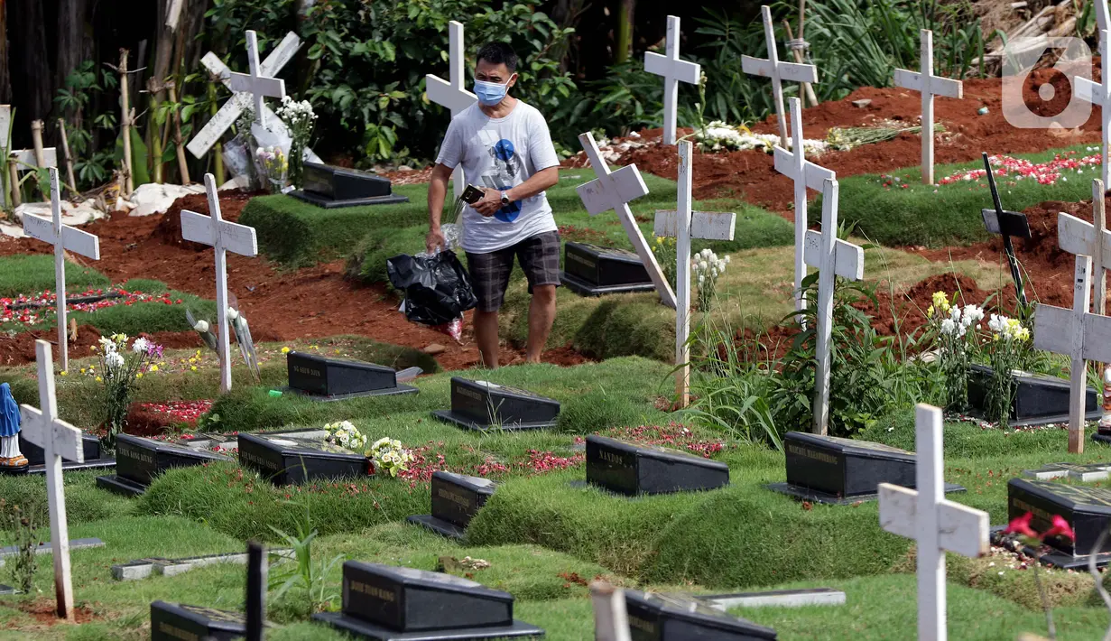 Warga berjalan di area pemakaman Kristen khusus dengan protokol COVID-19 di TPU Pondok Ranggon, Jakarta, Jumat (25/12/2020). Momen perayaan Natal 2020 dimanfaatkan sejumlah umat kristiani untuk berziarah mendoakan kerabat yang dimakamkan dengan protokol COVID-19. (Liputan6.com/Helmi Fithriansyah)