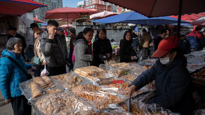 Sejumlah orang mengantre saat berbelanja kue di pasar di Beijing (20/11). (AFP Photo/Nicolas Asfouri)