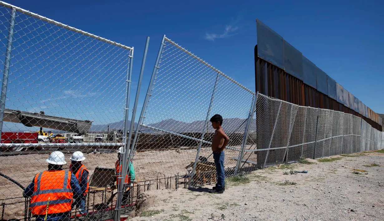 Seorang anak melihat pekerja dari Amerika Serikat saat membangun dinding perbatasan AS-Meksiko di Sunland Park, AS (09/9). Amerika Serikat dan Mexico merupakan dua negara yang memiliki batas geografis yang berdekatan. (REUTERS/Jose Luis Gonzalez)