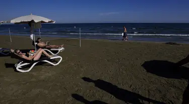 Sepasang suami istri menikmati cuaca hangat di pantai Makenzi di selatan kota Larnaca, Siprus, Senin (8/11/2021). Siprus mengalami cuaca seperti musim panas dalam beberapa hari terakhir dengan suhu tinggi yang tidak sesuai musim dan langit cerah. (AP Photo/Petros Karadjias)