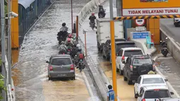 Sejumlah kendaraan melintasi Gerbang Tol Karang Tengah Barat 2 yang masih terendam banjir, Tangerang, Banten, Kamis (2/1/2020). Banjir setinggi betis orang dewasa masih menggenangi Gerbang Tol Karang Tengah Barat 2. (Liputan6.com/Angga Yuniar)