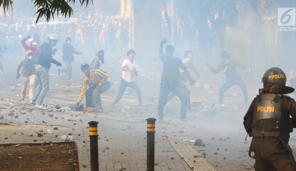 Massa melemparkan batu ke arah barisan polisi dalam unjuk rasa di sekitaran Gedung DPR RI, Jakarta, Senin (30/9/2019). Kericuhan pecah lantaran massa yang kebayakan terdiri dari pelajar tersebut berusaha masuk ke area depan DPR. (Liputan6.com/Angga Yuniar)