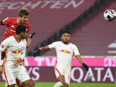 Striker Bayern Munich, Thomas Mueller, mencetak gol penyeimbang 3-3 lewat tandukan kepala dalam laga lanjutan Liga Jerman pekan ke-10 melawan RB Leipzig di Allianz Arena, Sabtu (5/12/2020). Bayern Munich bermain imbang 3-3 dengan RB Leipzig. (AFP/Andreas Gebert/Pool)