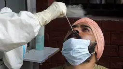 Petugas kesehatan mengambil sampel swab seorang pria untuk menguji virus corona Covid-19 di sebuah rumah sakit di Amritsar (2/9/2020). (AFP/Narinder Nanu)