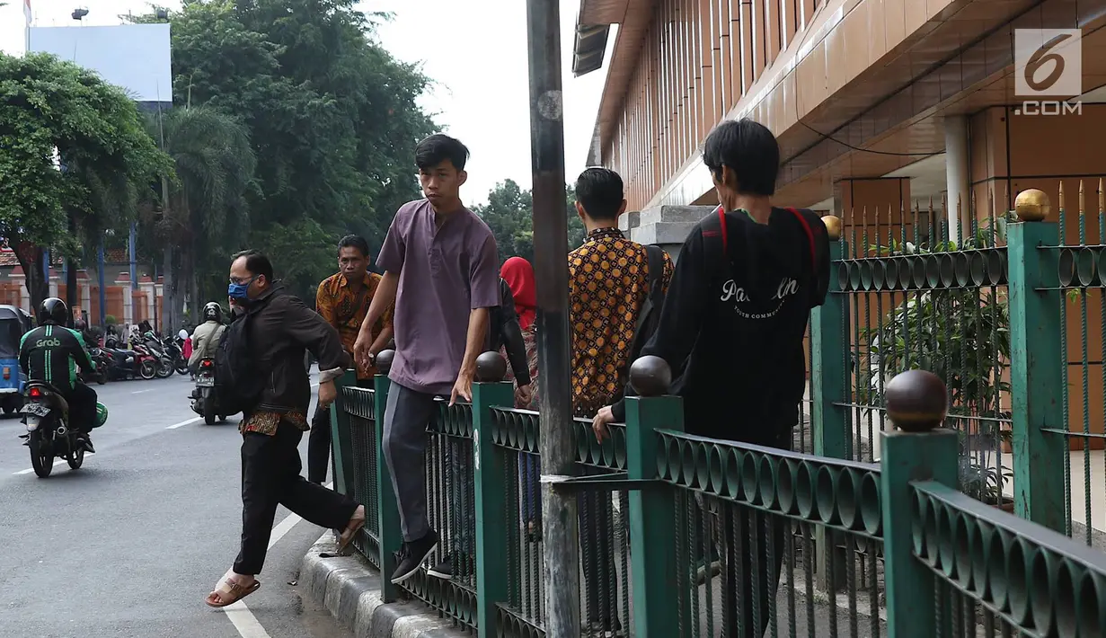 Penumpang melompati pagar pembatas untuk keluar dari Stasiun Cikini di Jakarta, Jumat (22/3). Jauhnya akses pintu masuk dan keluar stasiun menyebabkan sebagian orang mempersingkat waktu dengan melompat pagar pembatas. (Liputan6.com/Immanuel Antonius)