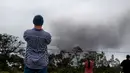 Joe Laceby (47) menyaksikan asap tebal yang berembus dari puncak gunung berapi Kilauea di Hawaii. Kamis (17/5). Para wisatawan tetap santai dan justru menjadikan letusan gunung ini sebagai objek wisata. (AP Photo/Caleb Jones)