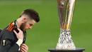 Reaksi kecewa kiper Manchester United, David de Gea saat berjalan melewati trofi Liga Europa 2020/2021 setelah dikalahkan Villarreal CF di Gdansk Stadium, Gdansk, 26 Mei 2021. Meskipun begitu, De Gea pernah mempersembahkan satu trofi Liga Europa untuk MU pada 2016/2017. Kala itu Setan Merah berhasil menang dengan skor 2-0 atas Ajax Amsterdam. (AFP/Pool/Maja Hitij)
