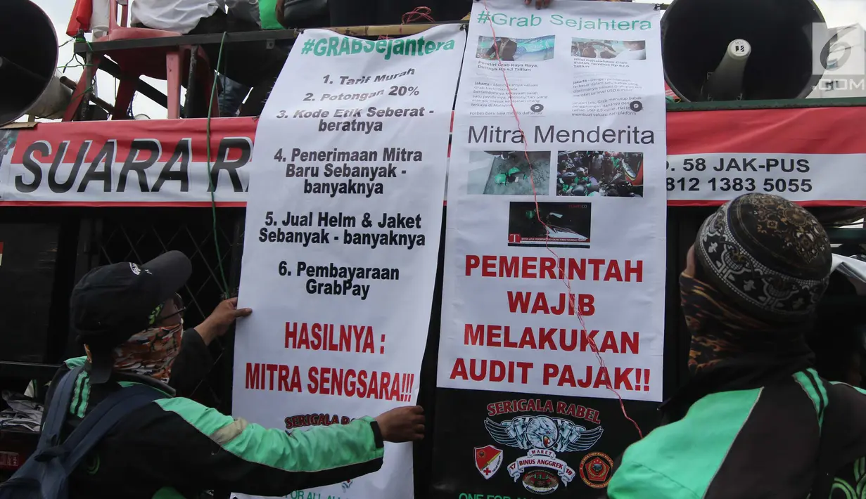 Pengemudi ojek online membentangkan poster yang berisi tuntutan mereka saat melakukan aksi di seberang Istana Merdeka, Jakarta, Selasa (27/3). (Liputan6.com/Arya Manggala)