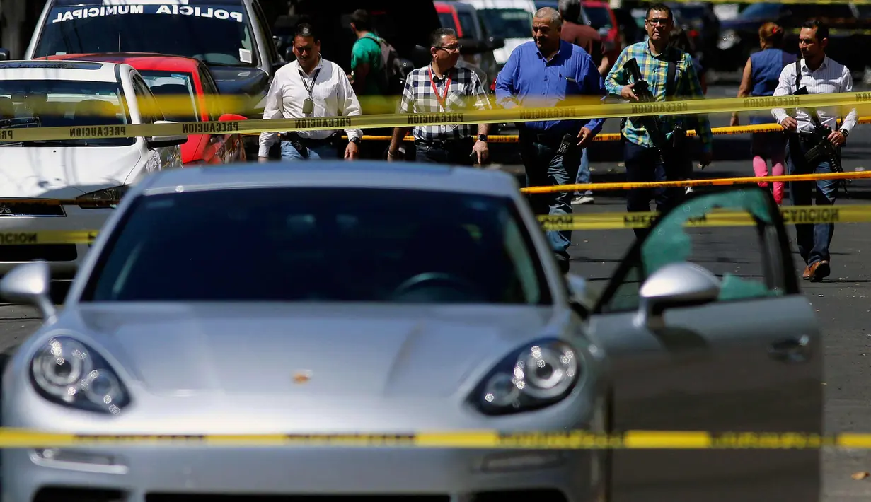 Petugas berjaga di lokasi penembakan mobil sport Porsche oleh orang tidak dikenal di Guadalajara, Meksiko, (14/3). Meksiko banyak mengalami kekerasan terkait dengan perdagangan narkoba. (AFP Photo/Ulises Ruiz)
