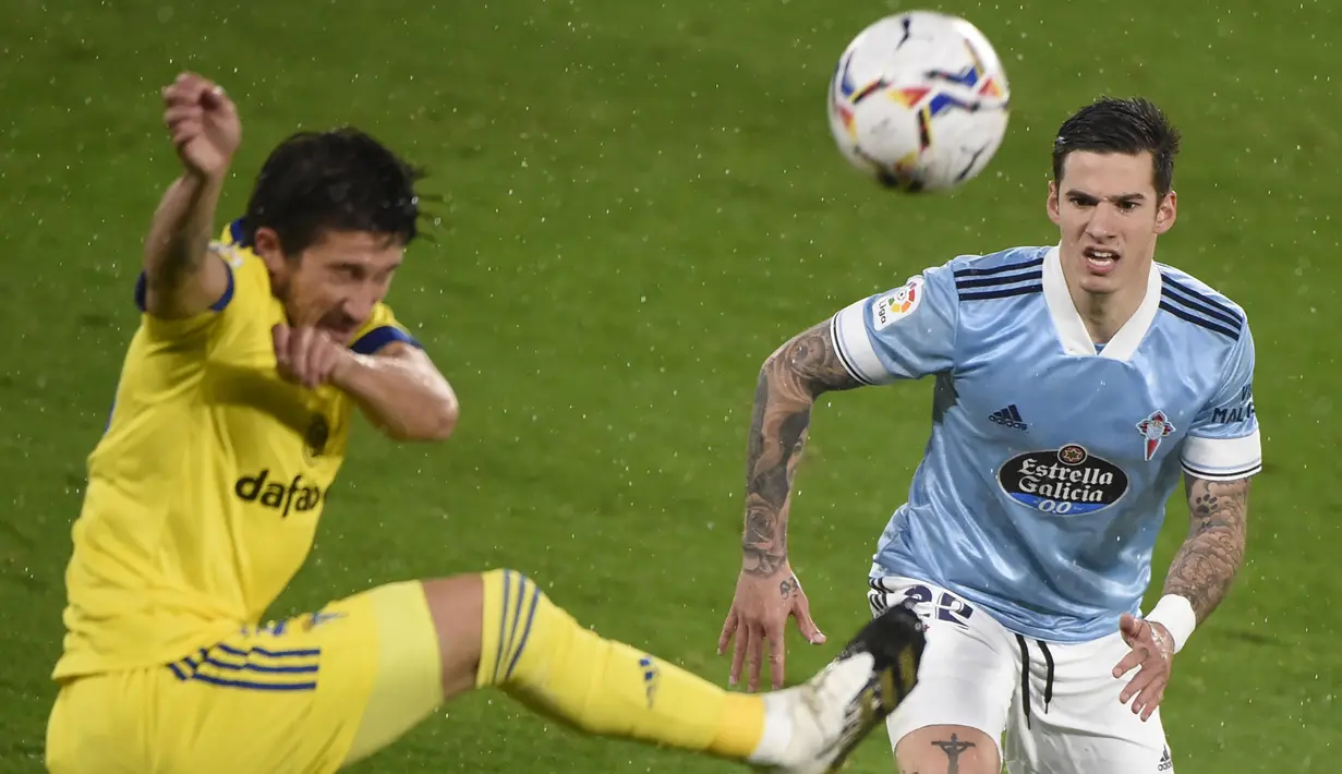 Penyerang Celta Vigo, Santi Mina, berebut bola dengan bek Cadiz, Alfonso Espino, pada laga lanjutan Liga Spanyol di Stadion Abanca Balaidos, Selasa (15/12/2020) dini hari WIB. Celta Vigo menang telak 4-0 atas Cadiz. (AFP/Miguel Riopa)