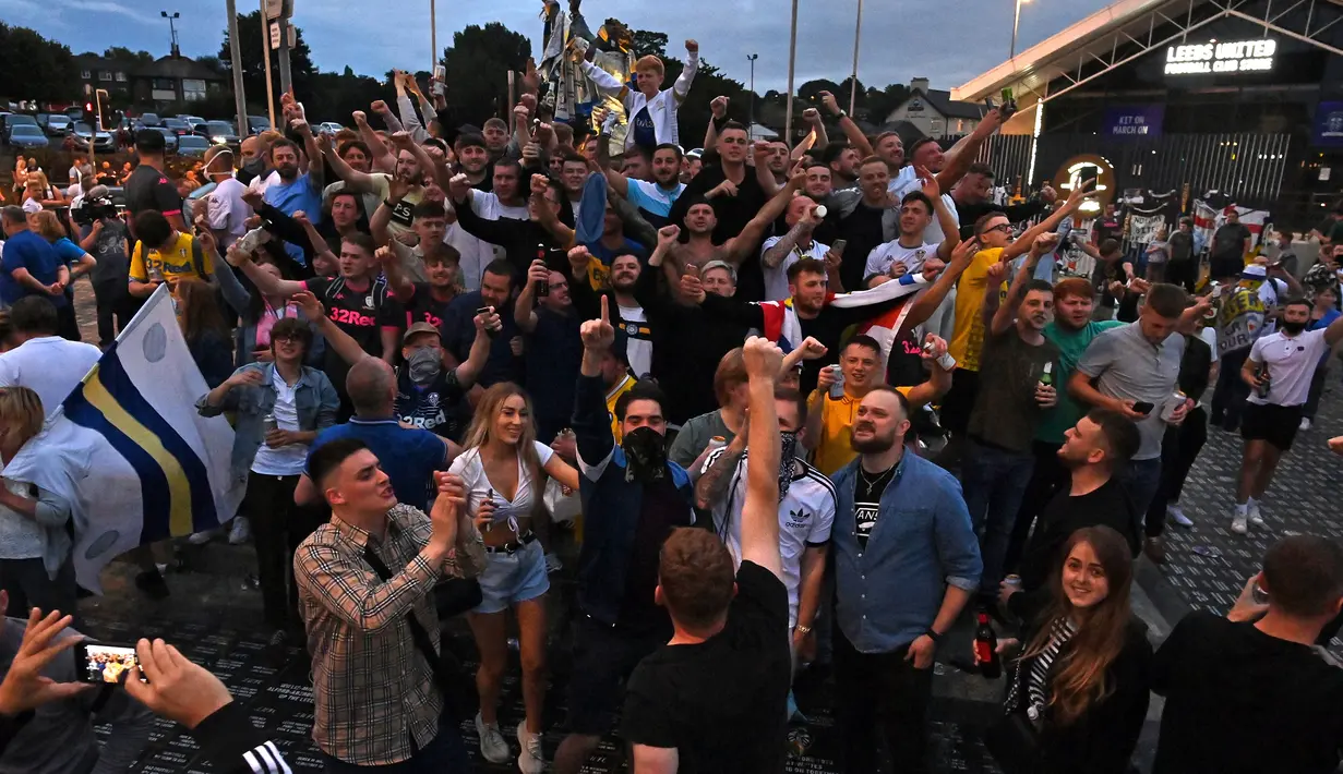 Suporter Leeds United merayakan keberhasilan timnya yang sukses kembali ke kompetisi Premier League di Elland Road, Leeds, Sabtu (18/7/2020). Leeds United dipastikan promosi ke Premier League musim 2020/2021 usai West Brom kalah 1-2 atas Huddersfield Town. (AFP/Paul Ellis)
