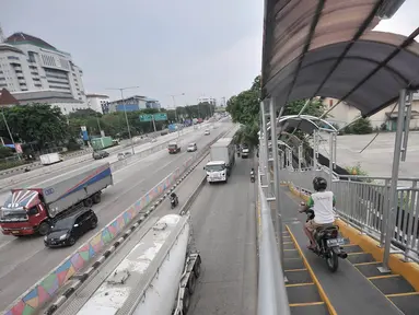 Pengendara sepeda motor melintasi JPO di Jalan Yos Sudarso, Jakarta, Senin (12/11). Aksi nekat yang dilakukan para pengendara sepeda motor demi mempersingkat rute jalan tersebut sangat mengganggu kenyamanan pejalan kaki. (Merdeka.com/Iqbal S. Nugroho)