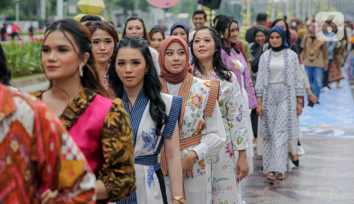 Sejumlah orang yang mengenakan batik berjalan di catwalk sepanjang Jalan Jenderal Sudirman, Jakarta, Minggu (2/10/2022). Kegiatan yang diikuti ratusan orang ini diselenggarakan oleh Bank Mandiri untuk menyambut Hari Batik Nasional yang jatuh setiap tanggal 2 Oktober 2022. (Liputan6.com/Faizal Fanani)