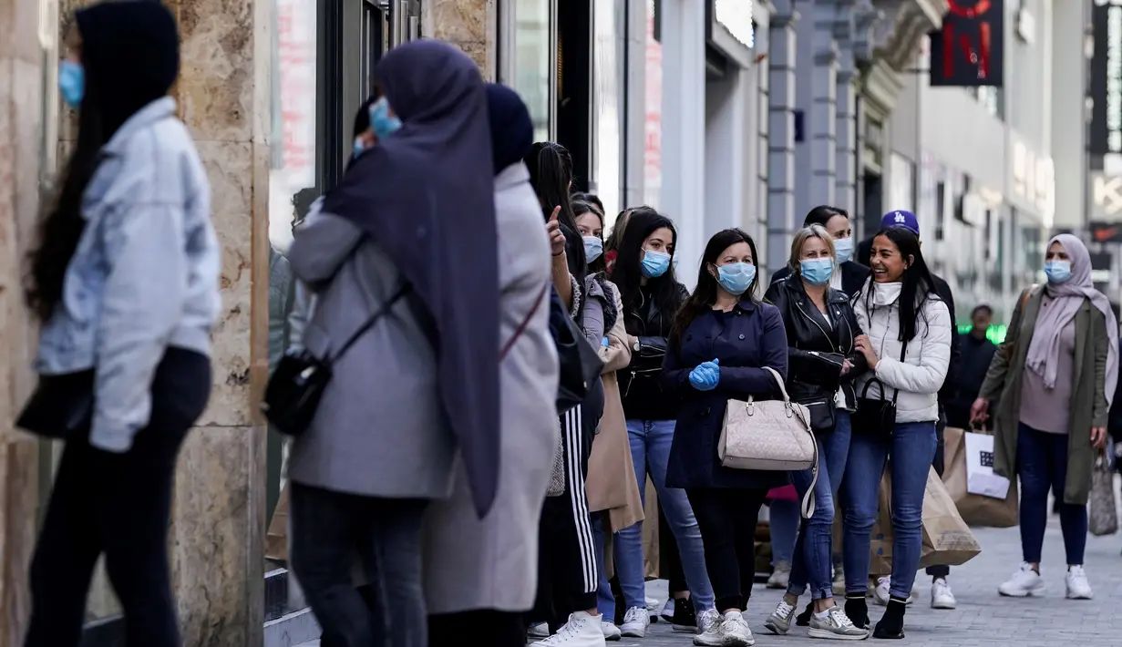 Pelanggan mengantre di pintu masuk sebuah toko pakaian pada hari pertama pelonggaran lockdown secara bertahap di Brussel, Senin (11/5/2020). Warga Belgia rela mengantre selama beberapa jam sebelum toko dibuka untuk berbelanja pertama kalinya sejak lockdown pada Maret lalu. (Kenzo TRIBOUILLARD/AFP)