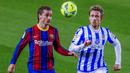 Penyerang Barcelona, Antoine Griezmann, berebut bola dengan pemain Real Sociedad, Nacho Monreal, pada laga Liga Spanyol di Stadion Camp Nou, Kamis (17/12/2020). Barcelona menang dengan skor 2-1. (AP/Joan Monfort)