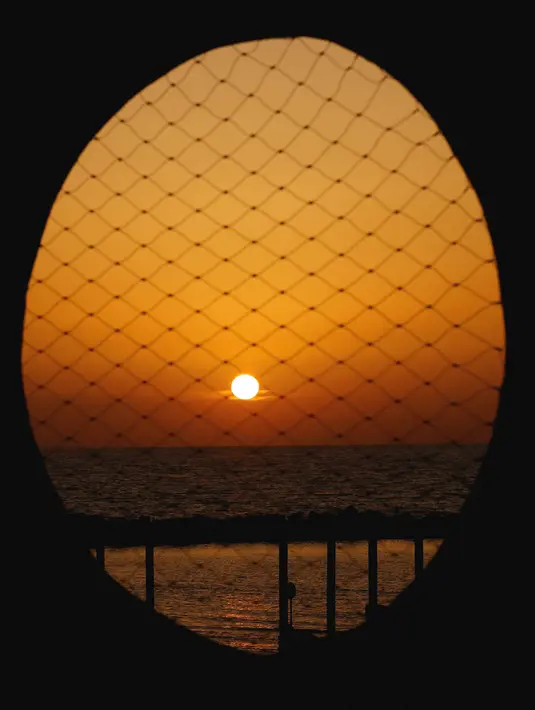 Matahari terbenam di pantai di kota pesisir Mediterania Israel Netanya, utara Tel Aviv (8/6/2021). Letak kota ini yang berjarak 14 kilometer dari pantai menjadikan kota ini sebagai tempat wisata yang populer. (AFP/ Jack Guez)
