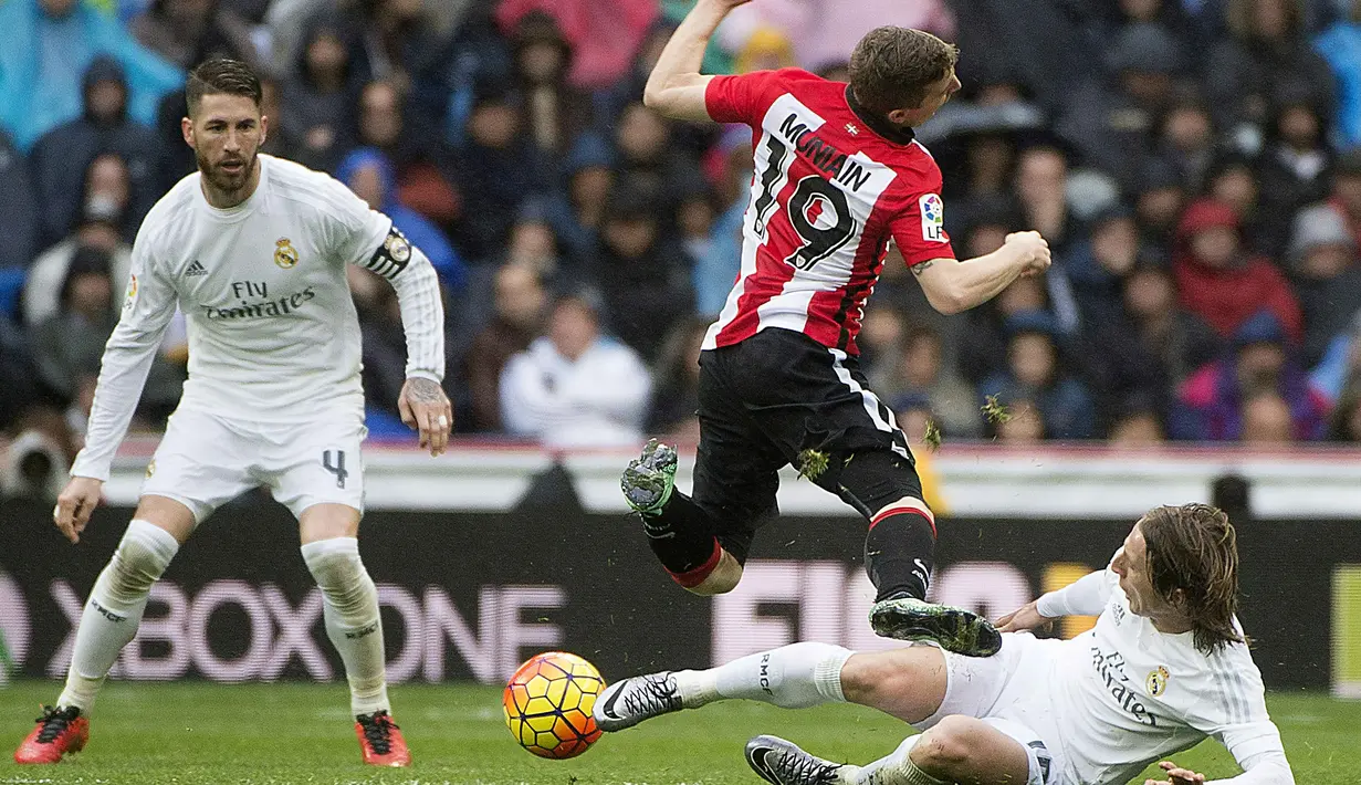 Pemain Athletic Bilbao, Iker Muniain (tengah) menerima tackle dari pemain Real Madrid, Luka Modric pada lanjtan La Liga Spanyol pekan ke-24 di Stadion Santiago Bernabeu,  Madrid, Sabtu (13/2/2016).  (AFP / Curto De La Torre)
