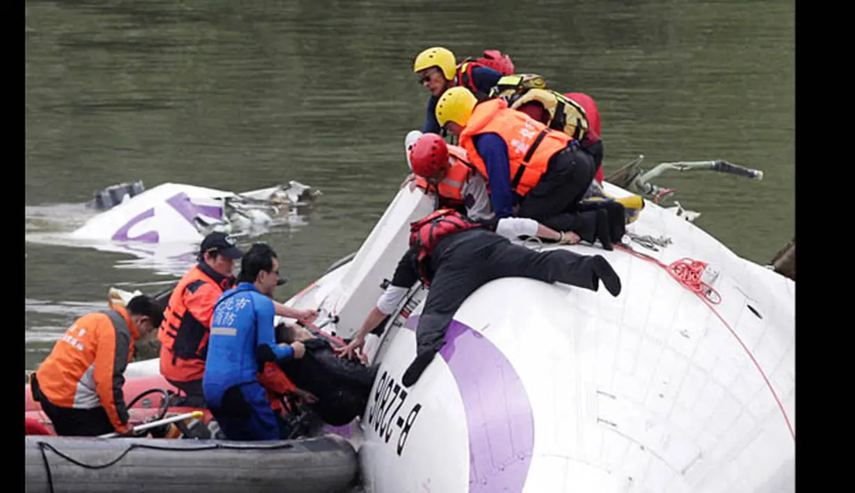 Petugas penyelamat menarik penumpang yang terjebak dalam badan pesawat yang tenggelam di Sungai Taipei, Taiwan, Rabu (4/2/2015). Dilaporkan 3 orang tewas dan puluhan lainnya terjebak. (REUTERS/Pichi Chuang)