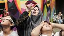 Pengunjung mengamati gerhana matahari cincin memakai kacamata khusus di Planetarium Taman Ismail Marzuki, Jakarta, Kamis (26/12/2019). Planetarium menyediakan sekitar 10 teleskop dan kacamata khusus agar pengunjung bisa menyaksikan gerhana matahari cincin dengan aman. (Liputan6.com/Faizal Fanani)