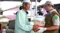 Pelaksana Tugas Wali Kota Bengkulu Dedy Wahyudi menyerahkan bantuan beras kepada warga. (LIputan6.com/Yuliardi Hardjo)