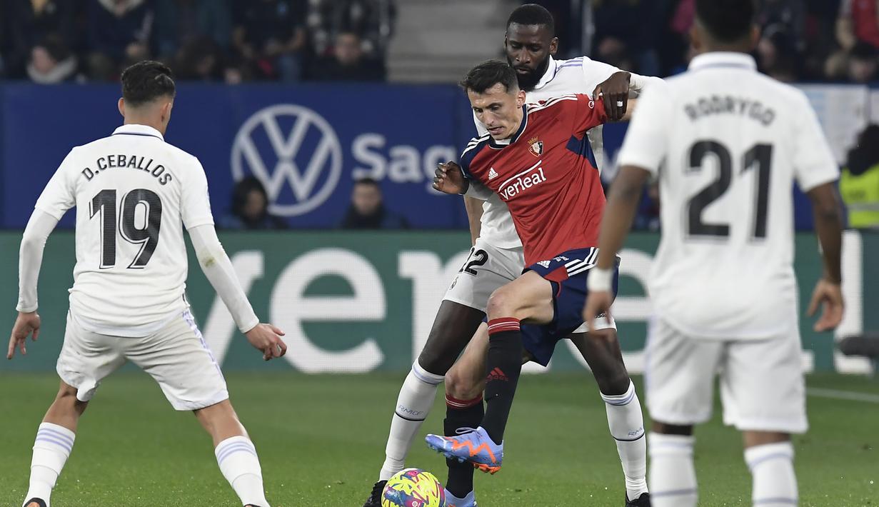 <p>Pemain Osasuna, Jon Moncayola mengontrol bola dari kawalan bek Real Madrid, Antonio Rudiger selama pertandingan lanjutan La Liga Spanyol di stadion El Sadar di Pamplona, Spanyol, Minggu (19/2/2023). Real Madrid menang atas Osasuna dengan skor 2-0. (AP Photo/Alvaro Barrientos)</p>