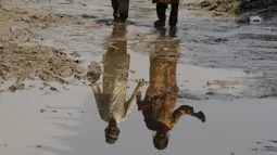 Seorang anak laki-laki dan perempuan tercermin dalam air di dekat rumah mereka yang dilanda banjir, di Charsadda, Pakistan, Rabu (31/8/2022). Para pejabat di Pakistan menyampaikan kekhawatiran Rabu atas penyebaran penyakit yang ditularkan melalui air di antara ribuan korban banjir saat air banjir dari hujan monsun yang kuat mulai surut di banyak bagian negara. (AP Photo/Mohammad Sajjad)