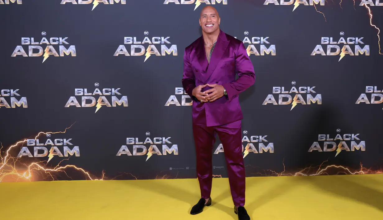 Dwayne Johnson berpose untuk fotografer saat tiba pada pemutaran perdana film 'Black Adam' di London, Inggris, 18 Oktober 2022. Dwayne Johnson memamerkan tubuh kekar bertatonya dengan tidak memakai pakaian di dalam tuksedo yang dia kenakan. (Photo by Vianney Le Caer/Invision/AP)